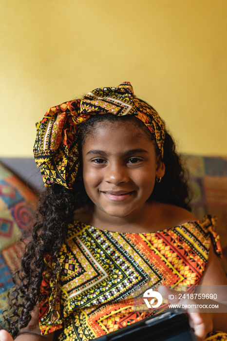 Retrato vertical de una hermosa niña afrocaribeña muy sonriente mirando a cámara en el interior de s