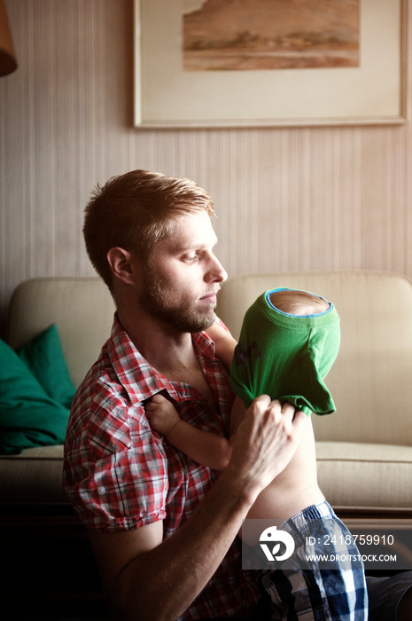 Father dressing his baby son (12-17 months)