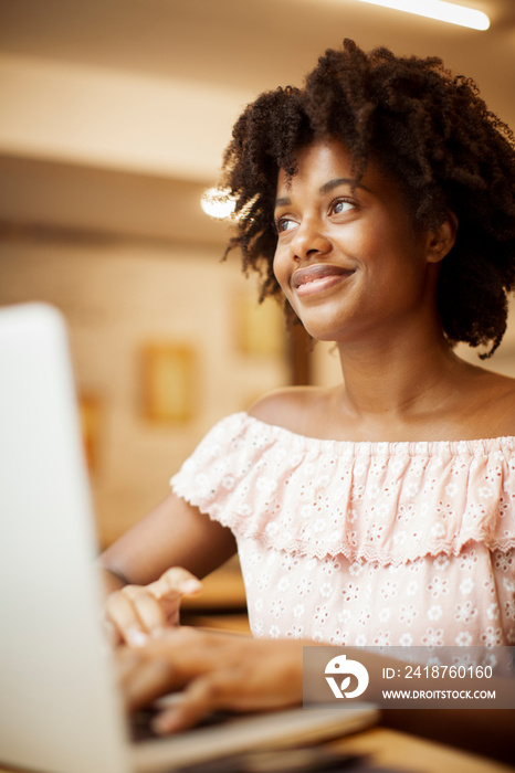 Low angle view of thoughtful businesswoman with curly hair using laptop computer while sitting in of