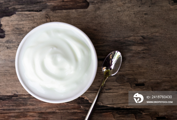 Yogurt greek white clean In bowl with spoon on a wooden background from top view.