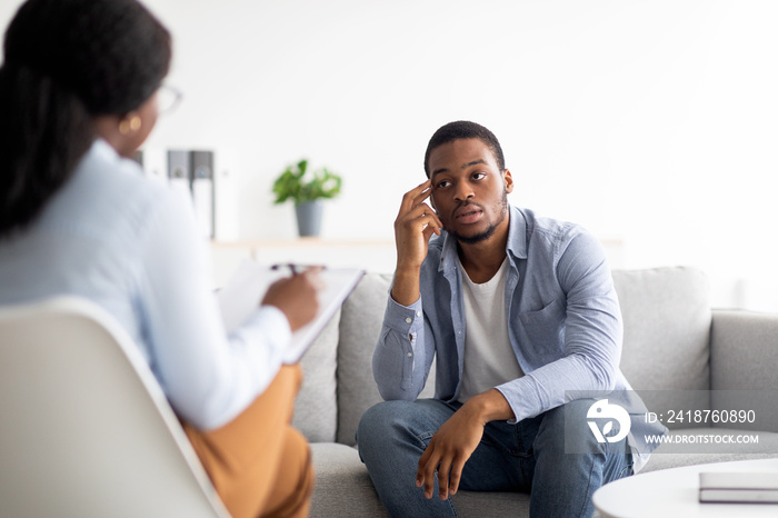 Stressed black man suffering from depression, counselor providing professional assistance at medical