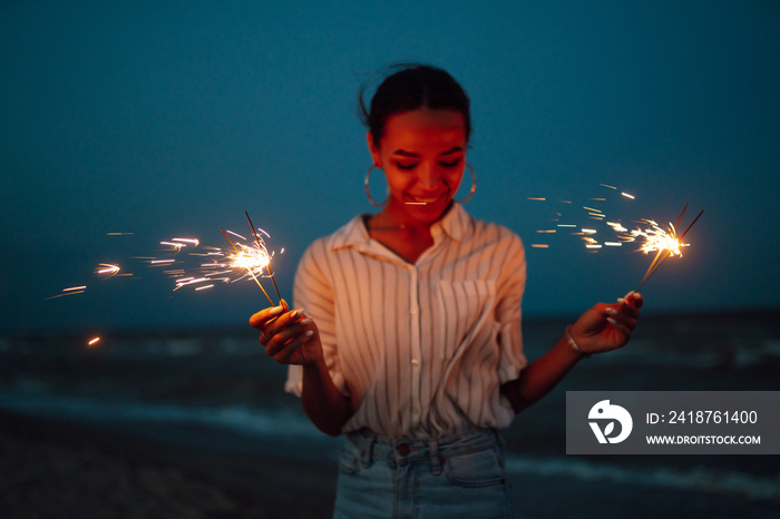 Female  hand holding burning Christmas sparkle on nature. Holidays, vacation, relax, travel and life