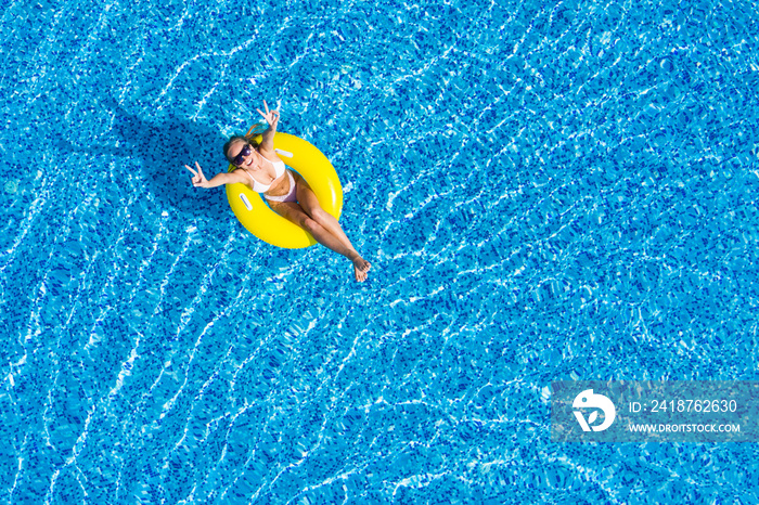 Beautiful woman in swimming pool aerial top view from above. Young girl in bikini relaxes and swims 