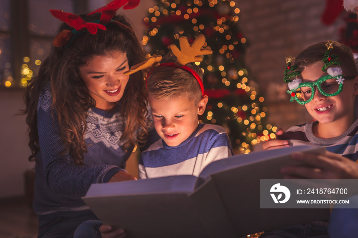 Parents reading fairytale to kids for Christmas Eve