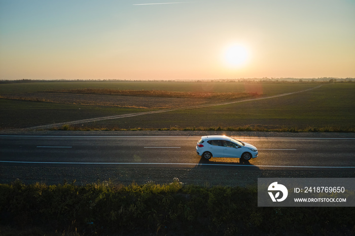 Aerial view of intercity road with blurred fast driving environment friendly electric car at sunset.