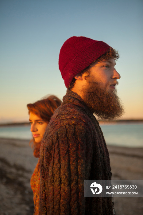 Young couple standing in evening sunlight on beach