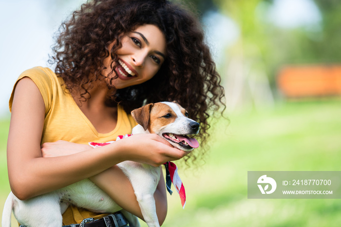 laughing woman looking at camera while stroking jack russell terrier dog