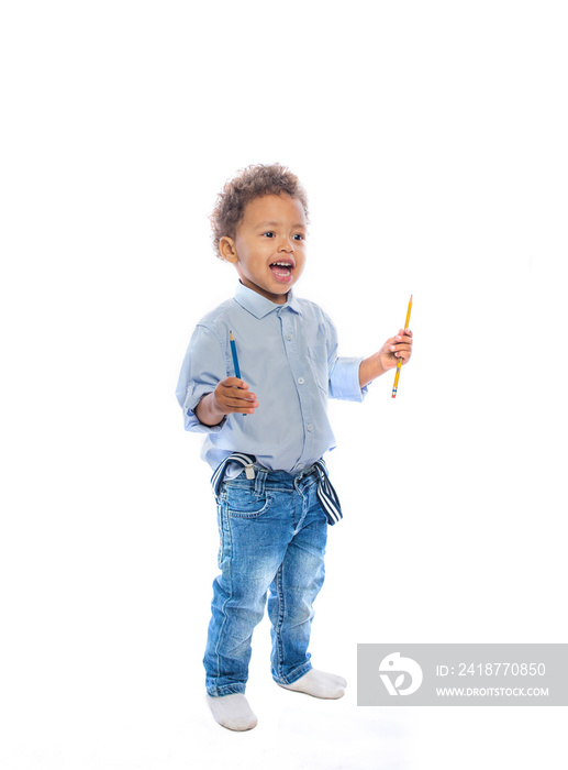 A small dark-skinned boy with curly hair in jeans and a light shirt stands in profile smiling and pu