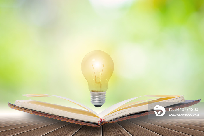 Open book and Light energy  light bulbs  Placed on a wooden floor Against the green bokeh background