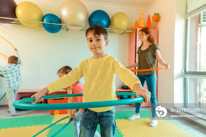 Joyful dark haired boy holding a hula hoop