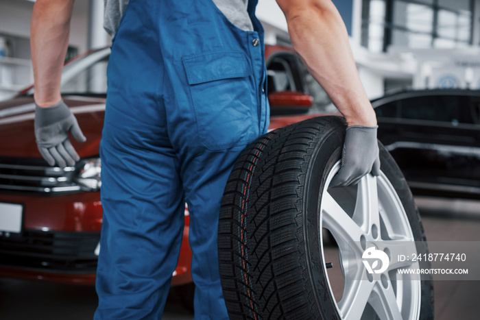 Mechanic holding a tire tire at the repair garage. replacement of winter and summer tires