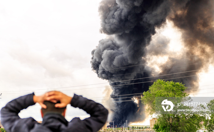 A huge smoke surprises a man a few meters from a fire