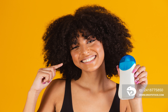 Afro woman holding a sunscreen in her hand with free space for text