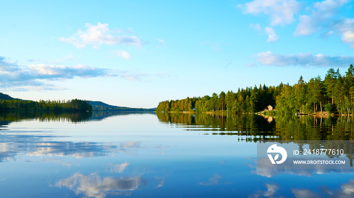 Wunderschöner Blick auf Stukas Ferienhäuser vom See aus in Schweden mit Spiegelungen im Wasser vom B