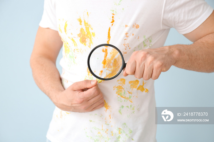 Man in dirty clothes and with magnifying glass on color background, closeup