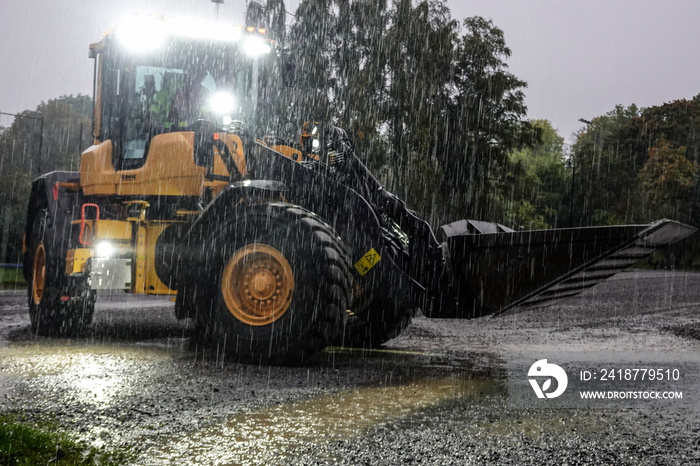 Stockholm, Sweden A large tractor with a scoop flattens out a parking lot in the rain to make room f