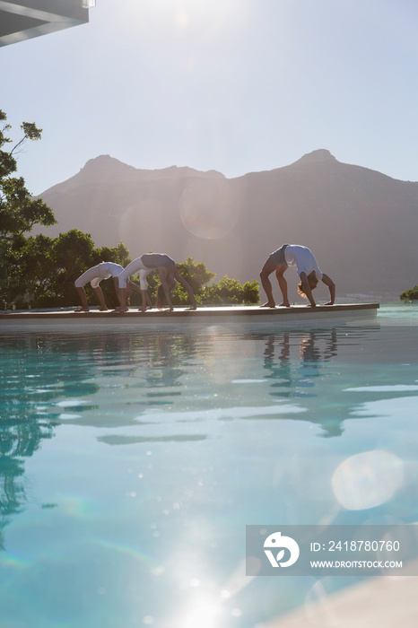 Yoga class practicing upward bow pose at sunny poolside