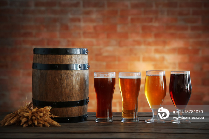 砖墙背景上有各种精酿啤酒、木桶和大麦穗的玻璃杯