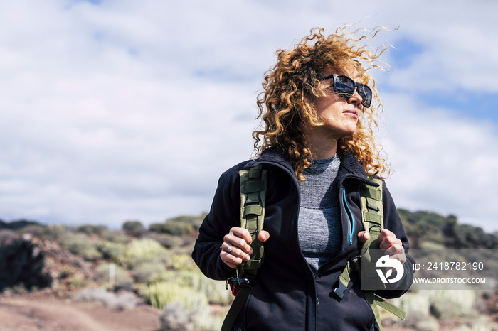 Beautiful curly hair middle age caucasian woman with backpack in trekking activity outdoor - female 