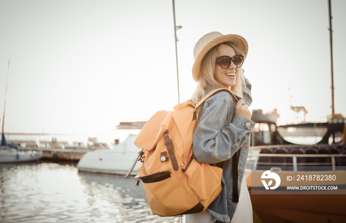 海上日出时背着大旅行背包的年轻女性游客。旅行和旅游理念