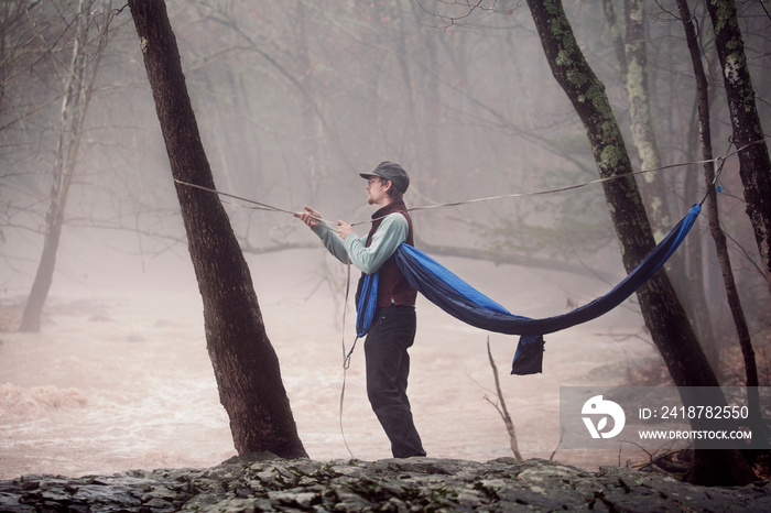 Young male hiker hanging hammock