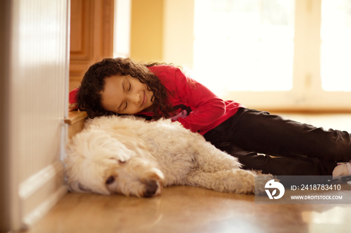 Girl (6-7) resting with dog on floor