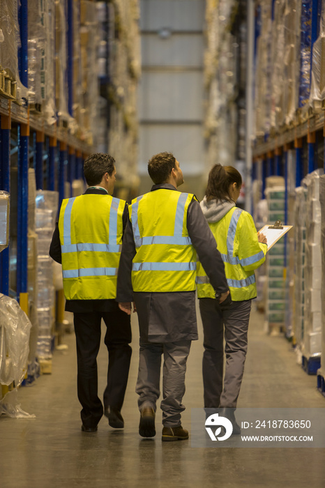 Workers in reflective vests in aisle of distribution warehouse