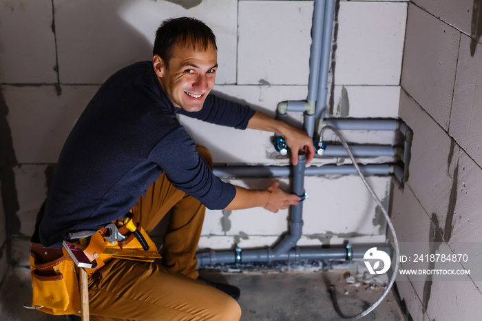 Young Male Plumber makes wiring of sewer pipes