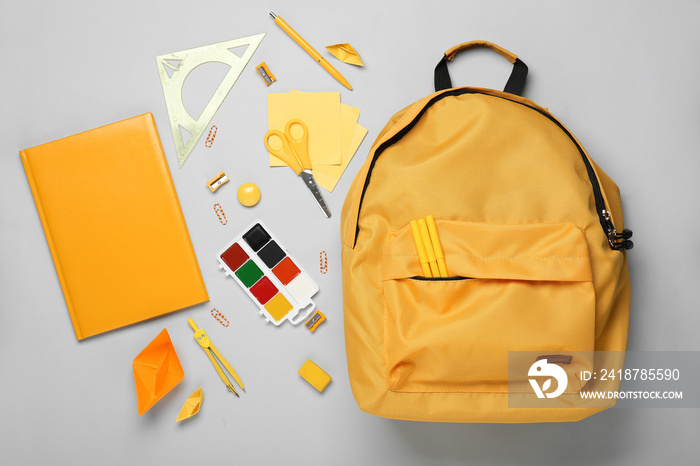 School backpack and stationery on light background