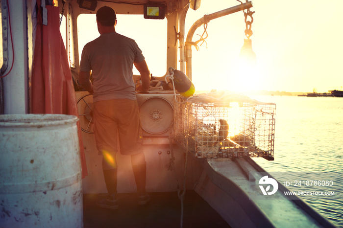 Rear view of fisherman sailing trawler in sea during sunset