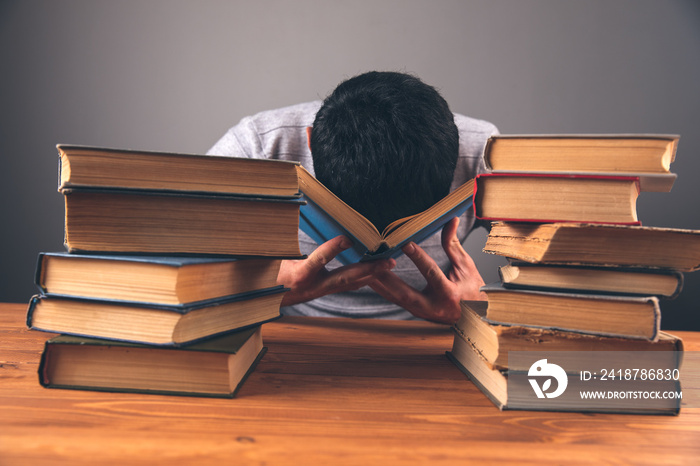 covered his face with his hands in front of books