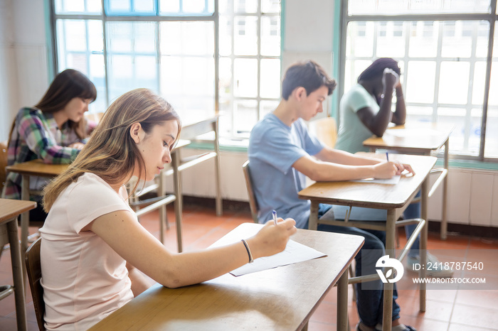 Group of multi ethnic high school students having test at classroom.