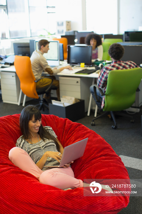 Creative businesswoman with laptop in beanbag chair