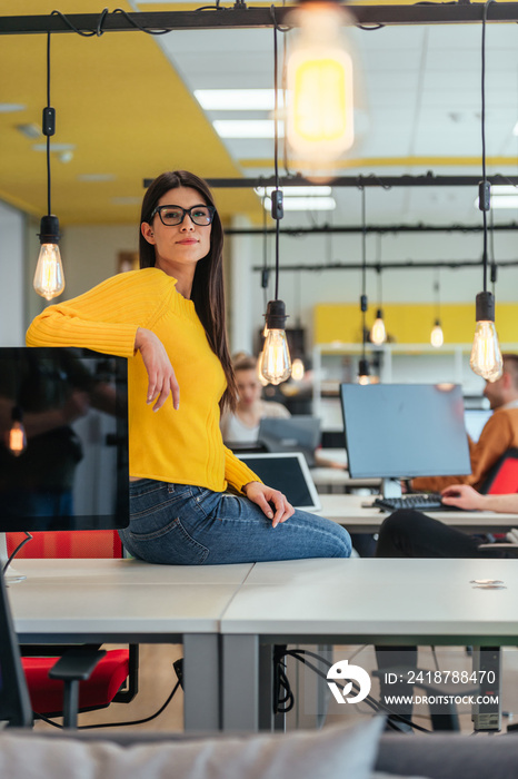 Female boss, manager executive posing in a modern startup office while being surrounded by her cowor