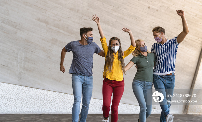 Young friends dancing together while wearing face mask outdoor - Happy people having fun in city aft