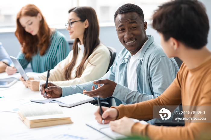 International group of people sitting at desk and talking