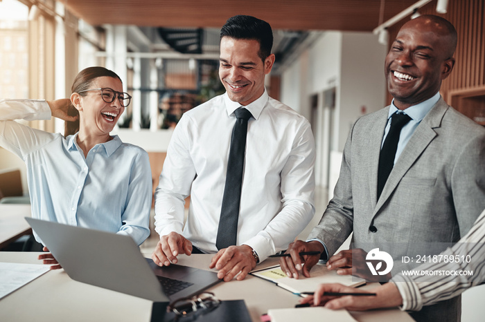 Diverse businesspeople laughing while working at an office table