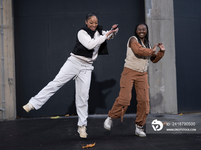 Female friends dancing to hip hop outdoors