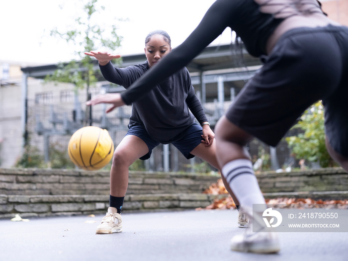 Two female friends playing basketball outdoors