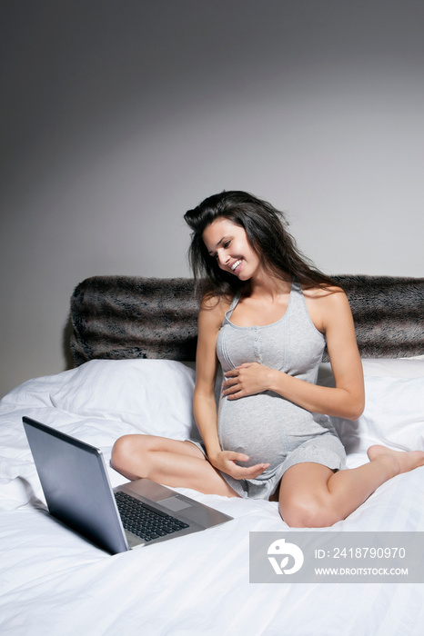 孕妇在床上使用笔记本电脑