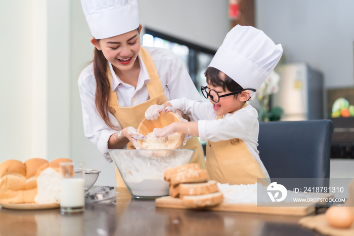 Happy family asian mom and son making bakery cake prepare delicious sweet food in the kitchen room f