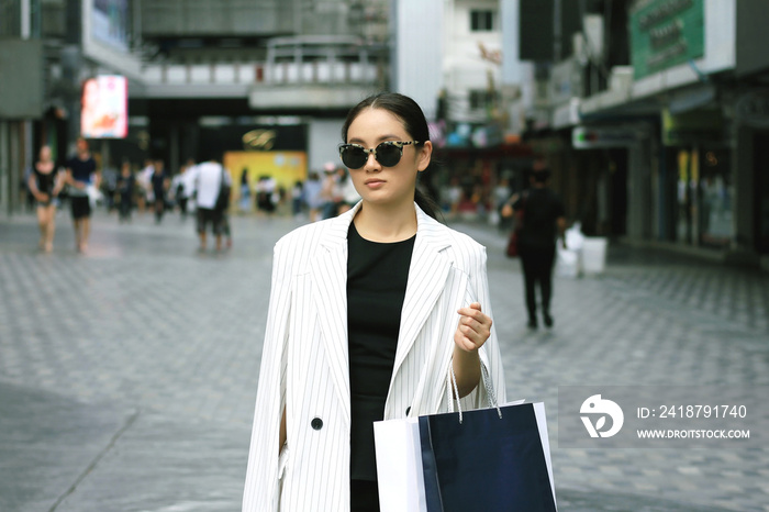 城市里的购物女人，街上拿着购物袋的时尚年轻女人的画像。