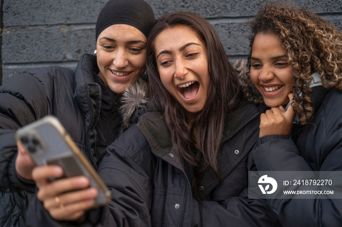 Three young women looking at smartphone