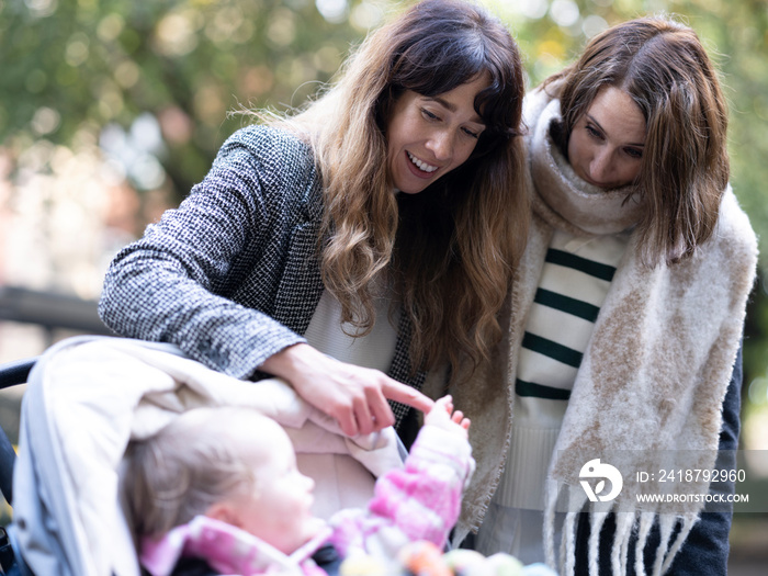 Women looking at baby in stroller at park�