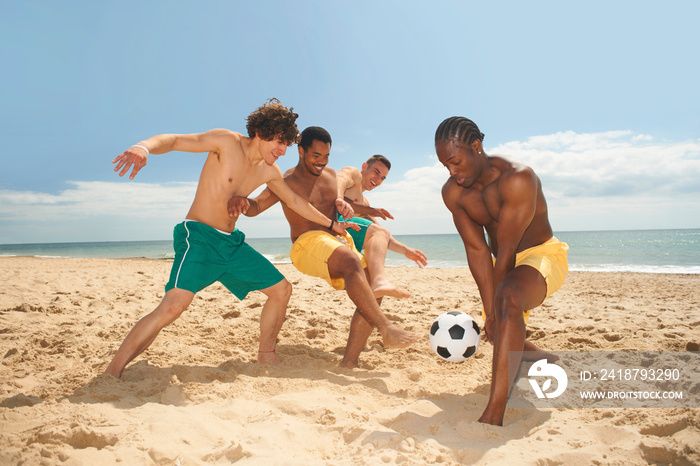 Friends playing football on beach