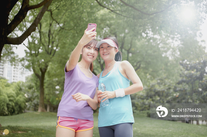 Female friends taking picture of themselves in park