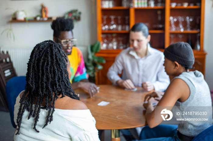 Group of friends playing cards together at home�