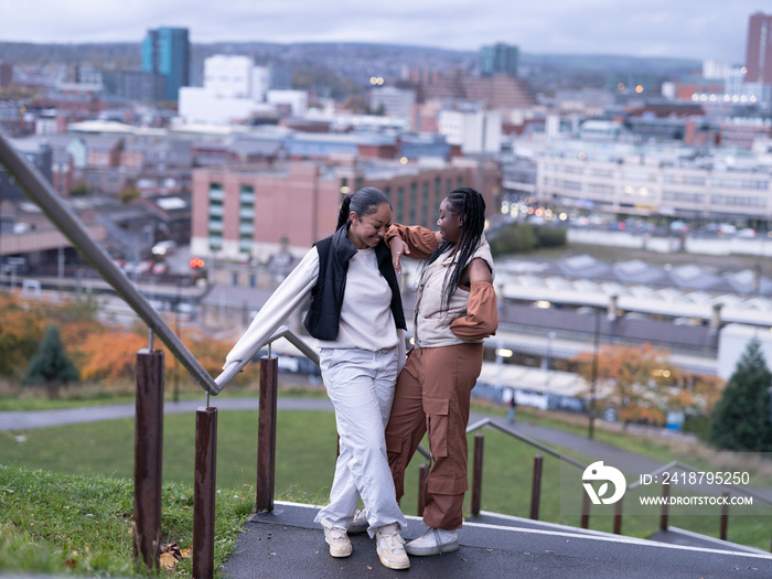 Smiling friends standing on steps in city