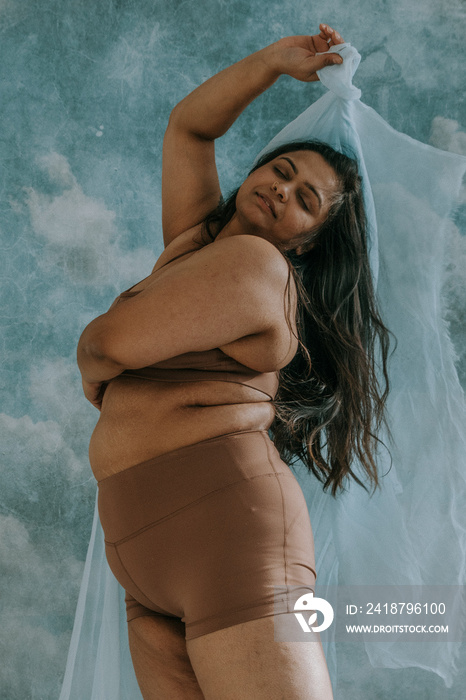 East Indian woman playing with blue fabric and looking peaceful