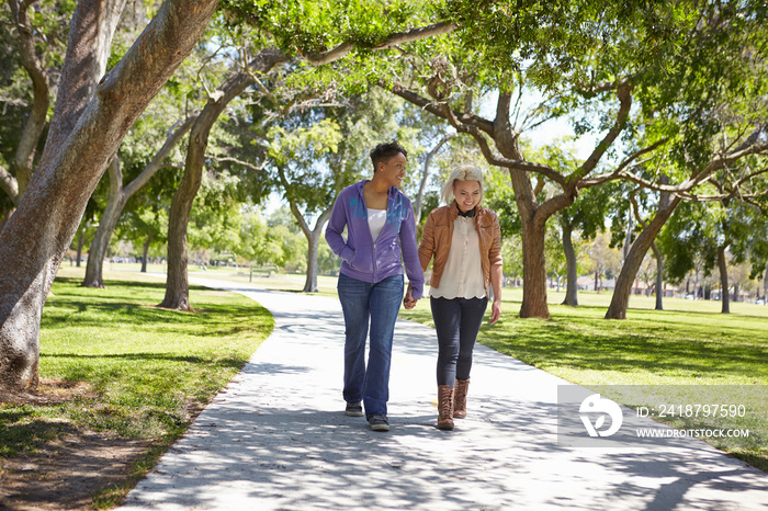 Lesbian couple holding hands and strolling in park